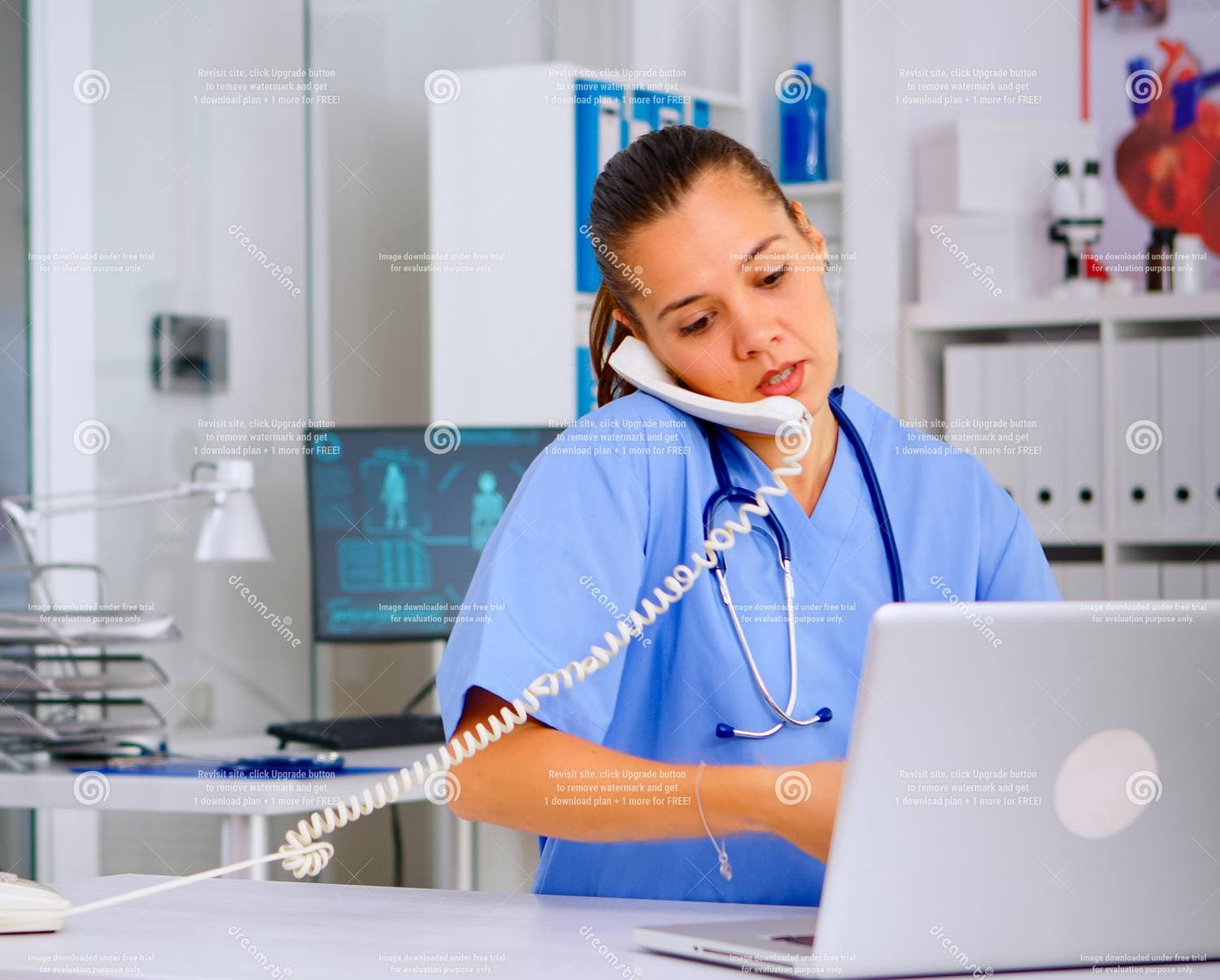 A clinical staff member on the phone at a desk, working at a laptop
